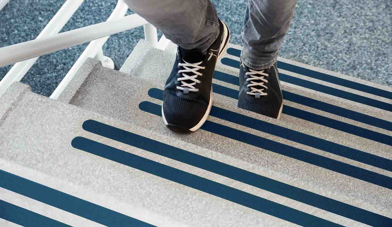 Ein Fußgänger läuft eine Treppe hinauf, worauf Antirutschstreifen geklebt sind