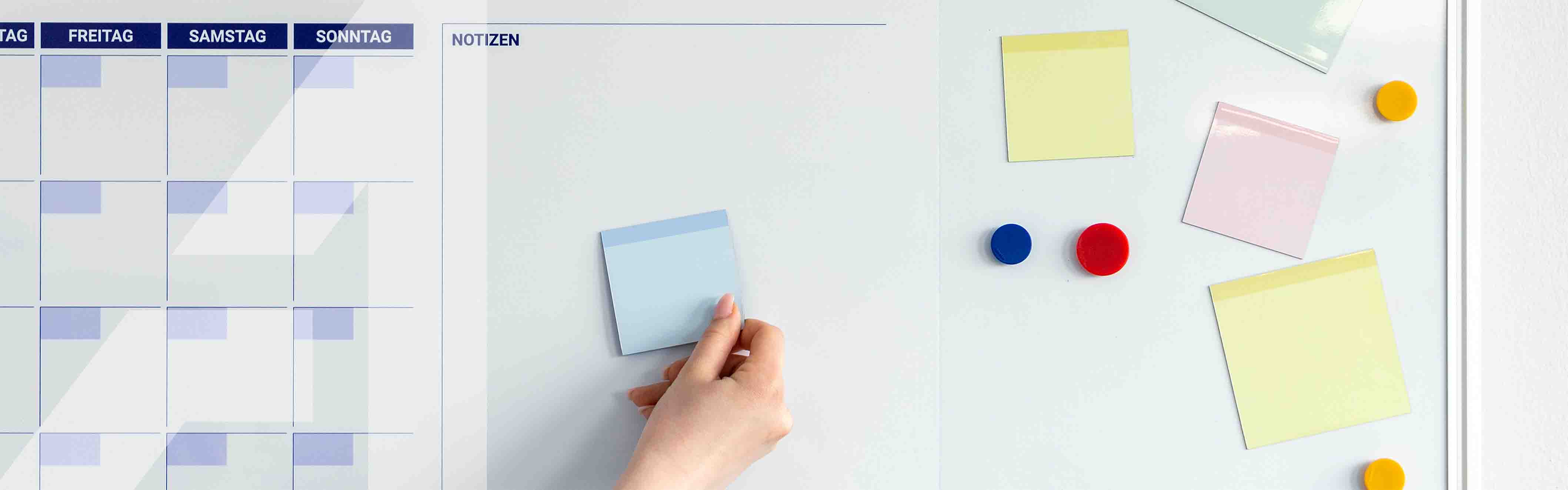 Whiteboard mit Kalender und verschiedenen Magneten und magnetischen Notizzetteln
