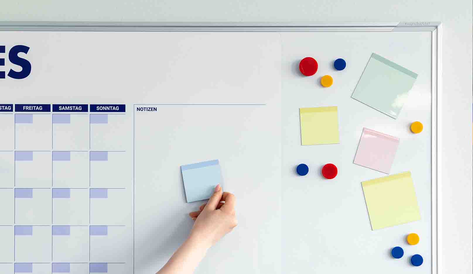Whiteboard mit Kalender und verschiedenen Magneten und magnetischen Notizzetteln